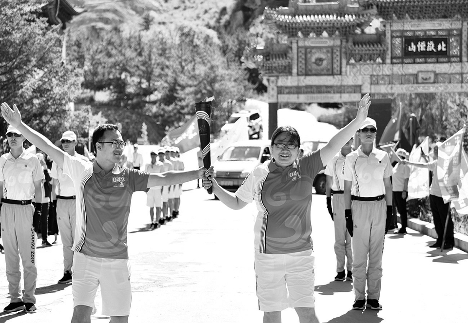 6月29日，在浑源县恒山景区内，火炬手孟银凤、贺斌正在传递火炬。王中勋摄